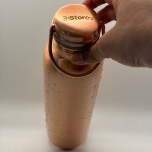 AM Stores copper bottle with carry-handle cap and water droplets.