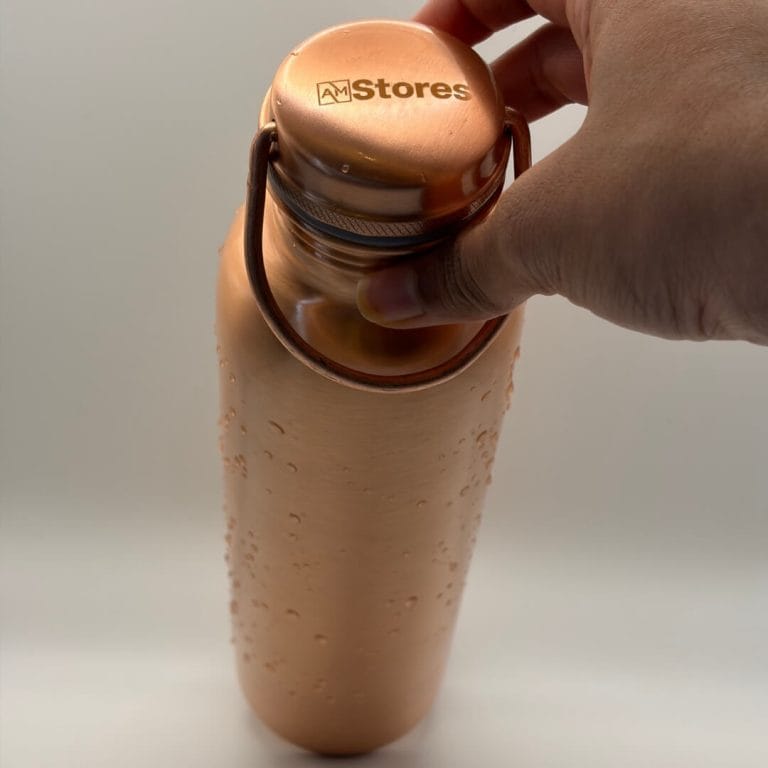 AM Stores copper bottle with carry-handle cap and water droplets.