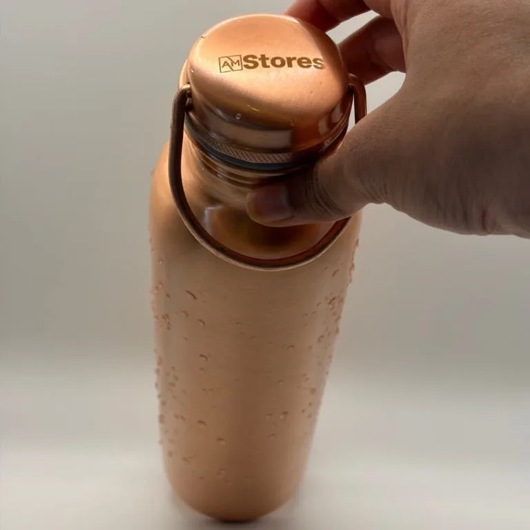 AM Stores copper bottle with carry-handle cap and water droplets.